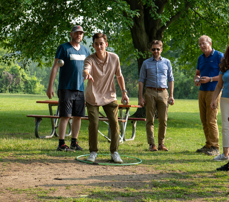 MCP student Noah Puleo (DiFeo Lab) 'pointe sa boule de pétanque' and scores a point at the Summer social event in Gallup Park (July 2023).