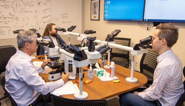 Dr. Douglas Fullen (left) working with two house officers in the dermatopathology sign-out room.